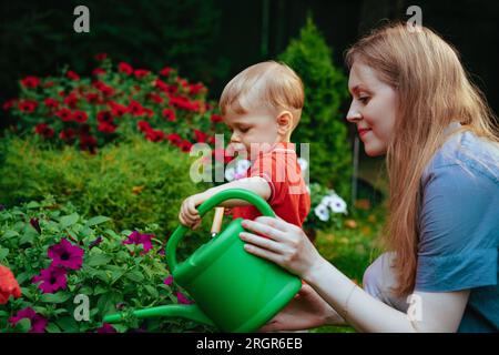 Junge Frau und ihre einjährige Kinderbetreuung Blumen im Garten Stockfoto