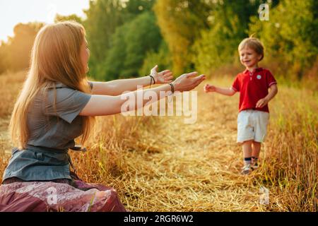 Die junge Mutter streckt ihre Hände vor ihrem zweijährigen Sohn aus Stockfoto