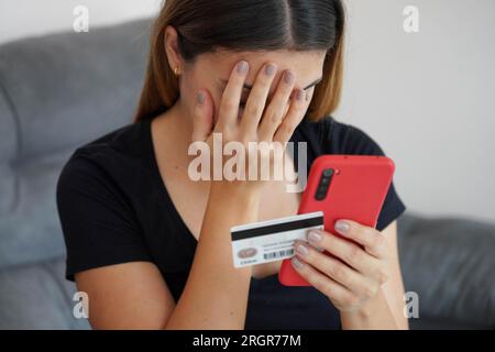 Digitaler Diebstahl. Verzweifelte junge Frau findet heraus, dass ihre Kreditkarte geklont und ihr Bankkonto geleert wurde. Cybersicherheitskonzept. Stockfoto