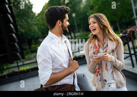 Glückliche junge Geschäftsleute, die im Freien chatten und digitale Geräte nutzen Stockfoto