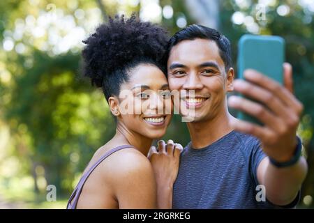 Ein wunderschönes junges Paar macht nach dem Training Selfie im Park, in Fitness-Läufer-Pose Stockfoto