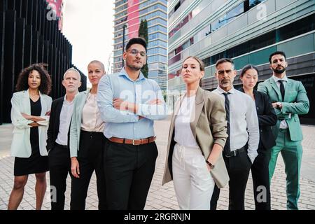Große Gruppe erfolgreicher Geschäftsleute, die am Arbeitsplatz zusammenstehen und in die Kamera schauen. Internationales Business-Team, das vor einem Arbeitsplatz steht. Treffen stolzer Start-up-Partner aus der Führungsebene. Hochwertiges Foto Stockfoto