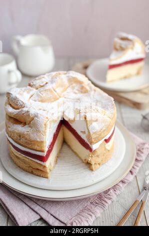 Polnischer Karpaten-Kuchen Karpatka. Creme Puffkuchen mit Erdbeeren. Holztisch und rosafarbener Hintergrund. Stockfoto