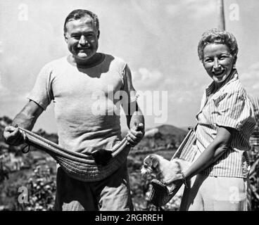 Havanna, Kuba: 20. März 1946 Autor Ernest Hemingway und seine vierte Frau Mary Welsh halten ihre Haustiere in Jai-Alai-Körben auf der Hemingway Farm in San Francisco de Paulo, einem Vorort von Havanna. Stockfoto