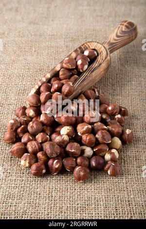 Haselnüsse und Holzschaufel auf rustikalem Hintergrund, Blick von oben Stockfoto