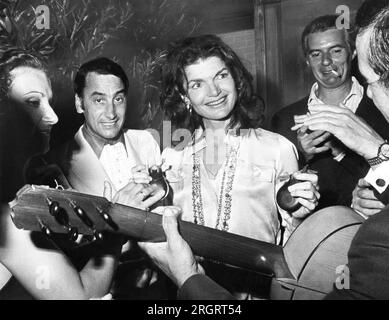 Vereinigte Staaten: Juni 1974 die ehemalige Jackie Kennedy, jetzt Frau Aristoteles Onassis, versucht mit einem Gitarrenspieler Kastagnetten zu klettern. Stockfoto