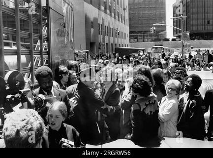 New York, New York: Am 12. Mai 1972 werden John Lennon und Yoko Ono von einem Polizisten unterstützt, der versucht, sich durch die Menge zu arbeiten, nachdem er das Einwanderungsamt am Broadway verlassen hat. Stockfoto