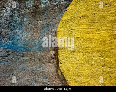 Textur einer alten Betonwand, übermalt mit blauen und hellbraunen Strichen und einem gezeichneten Halbkreis, übermalt mit gelber Farbe für A. Stockfoto