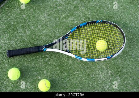 Tennisschläger mit Ball über grünem Kunstrasen. Vertikales Bild Stockfoto