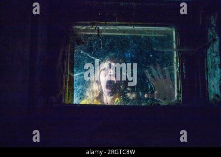Gruselige Frau hinter dem Fenster in der Nacht Halloween Horror Hintergrund Stockfoto