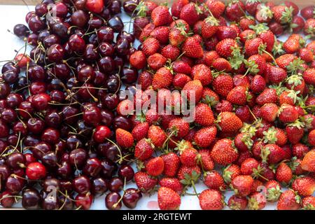Rote Kirschen und Erdbeeren auf einem Tablett zum Geburtstagsdessert Stockfoto