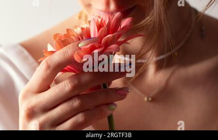 Rosa Blumen in der Hand auf weißem Hintergrund. Beauty und Frauengesundheitskonzept Stockfoto