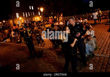 Berlin, Deutschland. 11. Aug. 2023. Polizeibeamte räumen die Brücke an der Admiralsbrücke nach einer Beschwerde von Bewohnern. Der Berliner Stadtteil Friedrichshain-Kreuzberg, der besonders bei Partygästen beliebt ist, möchte eine neue Methode anwenden, um sicherzustellen, dass die Partygänger auf den Straßen ruhiger und weniger nervig für die Bewohner sind. Zu diesem Zweck wurde ein im Gartenbau geprüfter Lärmmesser installiert. Kredit: Fabian Sommer/dpa/Alamy Live News Stockfoto