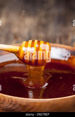 Fließend dicker und köstlicher süßer Honig fließt in ein Glasgefäß, ein natürliches und gesundes Nahrungsprodukt von Bienen, natürlicher Bienenhonig hat eine Viskose Stockfoto