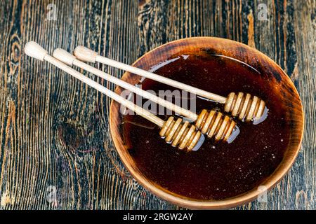 Ein Löffel für Honig zusammen mit hochwertigem Bienenhonig, ein alter Tisch, auf dem ein gesunder und süßer Bienenhonig steht, und ein spezieller Holzlöffel für B Stockfoto