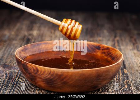 Ein Löffel für Honig zusammen mit hochwertigem Bienenhonig, ein alter Tisch, auf dem ein gesunder und süßer Bienenhonig steht, und ein hausgemachter Holzlöffel das Stockfoto