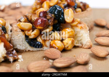 Knusprige Törtchen mit Haselnüssen, Erdnüssen und anderen Zutaten, Weizentörtchen mit Nüssen und getrockneten Früchten in Sahne-Karamell, Weizentörtchen mit Pfeffer Stockfoto