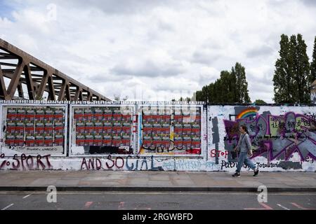 Man sieht Menschen an einer Mauer laufen, die vom Rat der Tower Hamlets umgemalt wurde, aber immer noch mit antichinesischen Parolen in der Brick Lane. Am 5. August bemalte das Royal College of Arts (RCA) die Wand weiß und bedeckte alle bestehenden Graffiti mit den 12 Kernwerten des Sozialismus während der Kulturrevolution, was eine hitzige Debatte zwischen lokalen Künstlern und chinesischen Gemeinschaften anlöste und die Verbreitung prochinesischer Propaganda in Frage stellte. Seit dem 8. August hat der Rat von Tower Hamlets eine Erklärung veröffentlicht, in der die Menschen aufgefordert werden, mit dem Malen weiterer illegaler Graffiti an der Wand aufzuhören Stockfoto