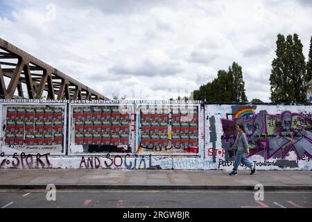 Man sieht Menschen an einer Mauer laufen, die vom Rat der Tower Hamlets umgemalt wurde, aber immer noch mit antichinesischen Parolen in der Brick Lane. Am 5. August bemalte das Royal College of Arts (RCA) die Wand weiß und bedeckte alle bestehenden Graffiti mit den 12 Kernwerten des Sozialismus während der Kulturrevolution, was eine hitzige Debatte zwischen lokalen Künstlern und chinesischen Gemeinschaften anlöste und die Verbreitung prochinesischer Propaganda in Frage stellte. Seit dem 8. August hat der Rat von Tower Hamlets eine Erklärung veröffentlicht, in der die Menschen aufgefordert werden, mit dem Malen weiterer illegaler Graffiti an der Wand aufzuhören Stockfoto