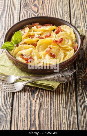 Italienisches traditionelles Gericht Girasoli Pasta mit Käse und Speck auf dem Holztisch. Vertikal Stockfoto