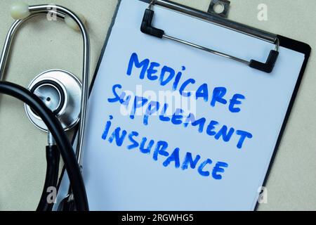 Konzept der Medicare-Zusatzversicherung Schreiben Sie auf ein Buch mit auf einem Holztisch isoliertem Stethoskop. Stockfoto