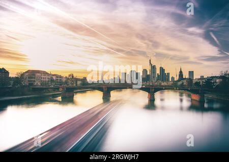 Blick auf Frankfurt bei Sonnenuntergang. Aufnahme mit Hintergrundbeleuchtung und Blick auf die Skyline. Hochhäuser von Banken und Versicherungsgesellschaften im Finanzdistrikt Stockfoto