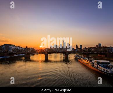 Blick auf Frankfurt bei Sonnenuntergang. Aufnahme mit Hintergrundbeleuchtung und Blick auf die Skyline. Hochhäuser von Banken und Versicherungsgesellschaften im Finanzdistrikt Stockfoto