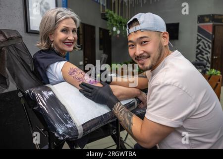 Tattoo-Meister-Tattoo auf Frauenarm Stockfoto