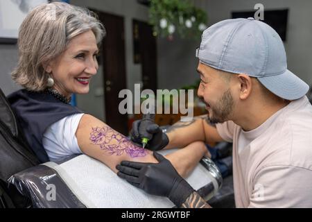 Tattoo-Meister-Tattoo auf Frauenarm Stockfoto