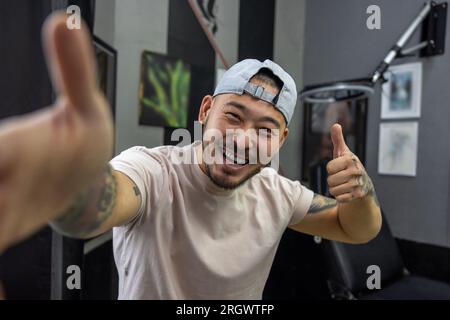 Asiatischer junger Mann in einem Tattoo-Salon Stockfoto
