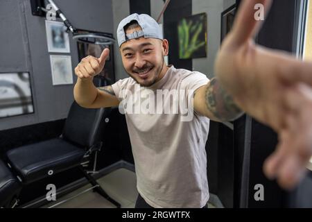 Asiatischer junger Mann in einem Tattoo-Salon Stockfoto