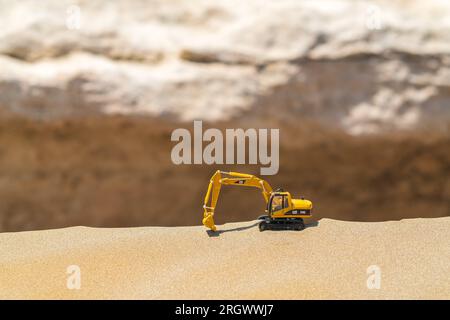 Caterpillar-Bagger mit Spielzeugmodell auf Sand in der Wüste Stockfoto