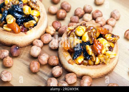 Knusprige Törtchen mit Haselnüssen, Erdnüssen und anderen Zutaten, Weizentörtchen mit Nüssen und getrockneten Früchten in Sahne-Karamell, Weizentörtchen mit Pfeffer Stockfoto