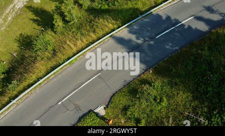 Eine atemberaubende Luftaufnahme von einer Drohne, die die atemberaubende Schönheit des Alpenwaldes und eine gewundene Straße inmitten der majestätischen Alpen zeigt Stockfoto