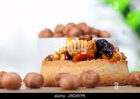 Knusprige Törtchen mit Haselnüssen, Erdnüssen und anderen Zutaten, Weizentörtchen mit Nüssen und getrockneten Früchten in Sahne-Karamell, Weizentörtchen mit Pfeffer Stockfoto