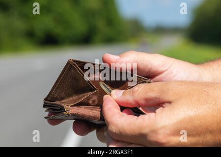 Ein Mensch nimmt einen Euro aus seiner Brieftasche, steht auf der Straße, ein Konzept von Geldmangel für Reisen Stockfoto