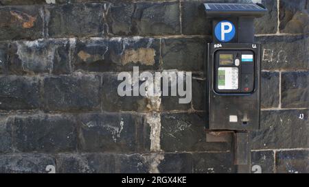 Parkautomat neben einer alten Steinmauer. Irland, Dublin 06.06.2023. Stockfoto