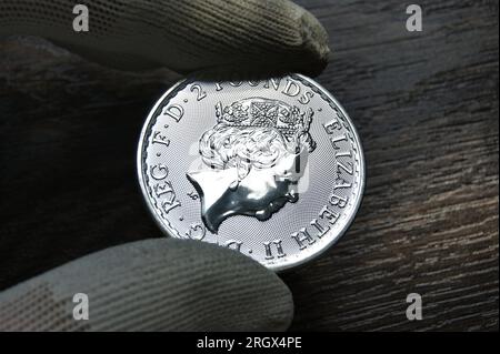 Eine britische Silbermünze in den Händen eines Numismatikers. Britische Silbermünze 2 Pfund Proof. Stockfoto