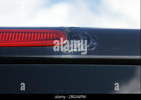 Rost an der Karosserie eines schwarzen Autos in der Nähe der Bremsleuchte. Fahrzeug defekt. Stockfoto