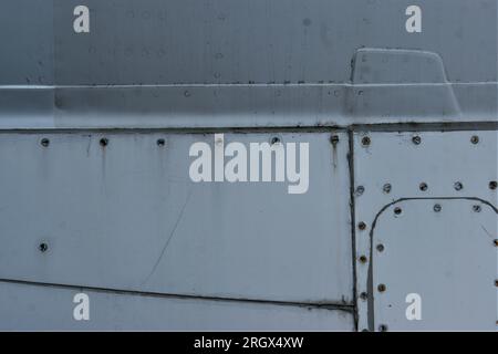 Fragment eines alten Flugzeugrumpfes. Metallischer Hintergrund mit Schrauben und Nieten. Stockfoto