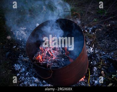 Müll im Tank verbrennen. Müllverbrennung in einem Eisenkübel. Flammen. Stockfoto