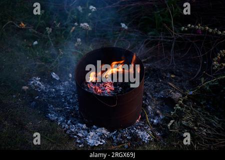 Müll im Tank verbrennen. Müllverbrennung in einem Eisenkübel. Flammen. Stockfoto