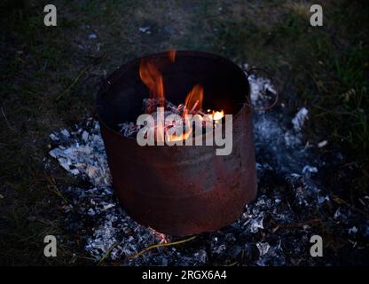 Müll im Tank verbrennen. Müllverbrennung in einem Eisenkübel. Flammen. Stockfoto