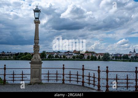 Schwerin, Mecklenburg-Vorpommern Deutschland, 07 06 2023: Blick über den Schweriner See auf das Stadtpanorama und eine alte Straßenlaterne mit einem Zaun im Vordergrund Stockfoto