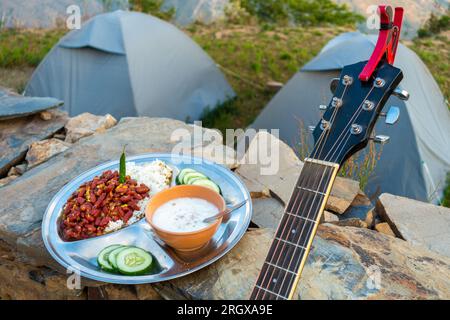 Uttarakhand Camping Vibes: Rajma-Chawal-Festmahl mit Quark und Salat, gepaart mit Zelten und Gitarrenstrumen. Authentische nordindische Aromen inmitten der Natur Stockfoto