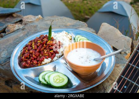 Uttarakhand Camping Vibes: Rajma-Chawal-Festmahl mit Quark und Salat, gepaart mit Zelten und Gitarrenstrumen. Authentische nordindische Aromen inmitten der Natur Stockfoto