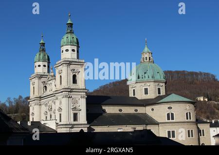 Alternativer Blick auf das berühmte Wahrzeichen der Salzburger Kathedrale, das hier gezeigt wird, mit Blick auf die Südwestfassade, die im Winter an einem klaren, sonnigen Tag von der Sonne erhellt wird Stockfoto