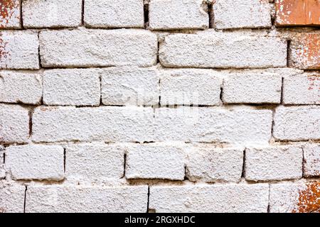 Alte, verfallene Wand aus beschädigten roten Ziegeln, mit einer weißen Wischwäsche befleckt, leerer Platz für Notiz. Stockfoto