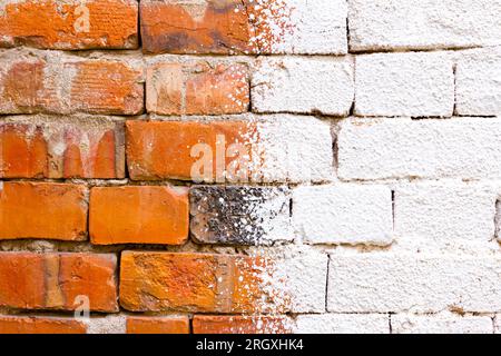 Alte, verfallene Wand aus beschädigten roten Ziegeln, mit einer weißen Wischwäsche befleckt, leerer Platz für Notiz. Stockfoto