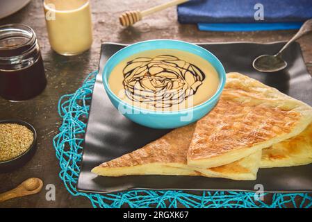 Ein köstliches, wirbelndes Muster aus Tahini-Sauce und Melasse. Traditioneller Tahini und Melasse-Dip aus dem Nahen Osten. Stockfoto